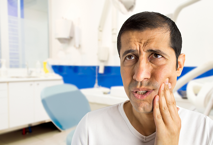 Man holding his cheek in pain while visiting an emergency dentist