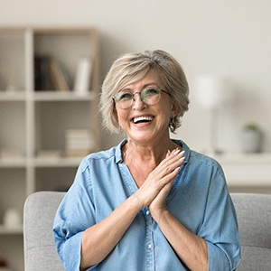 Senior woman with glasses smiling on couch at home