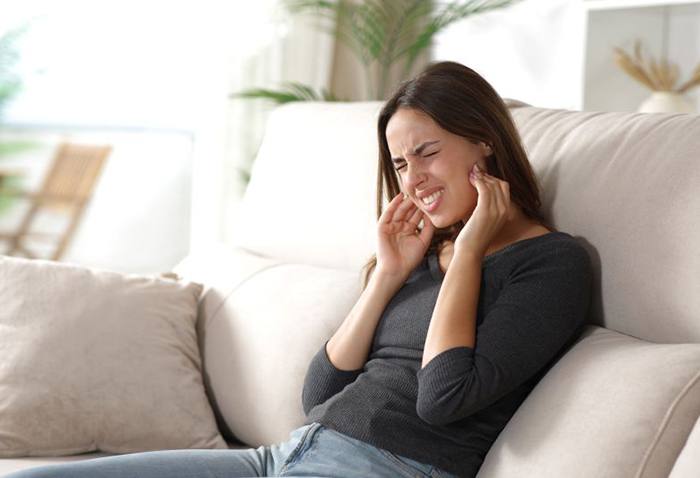 Woman suffering from pain of TMJ disorder